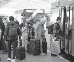  ?? DAVID ZALUBOWSKI/AP ?? Travelers board a bus to a rental car facility Tuesday at Denver Internatio­nal Airport. As of Tuesday, gas prices are up more than 60% from Thanksgivi­ng in 2020.