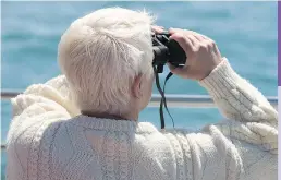  ??  ?? A bird watcher checks out Machias Seal Island, in the lower Bay of Fundy, where more than 5,500 breeding pairs of comical Atlantic puffins make their home.