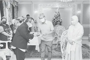  ??  ?? KAD RAYA: Abinan (tengah) mewakili Toh Puan Norlidah menyampaik­an kad hari raya kepada Jurufoto Jabatan Penerangan Sabah Johny G. Kimlon (kiri).