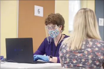  ?? H John Voorhees III / Hearst Connecticu­t Media ?? Jennifer Barabas has her informatio­n taken down by pharmacist Kathy Haddy before she receives her first dose of COVID-19 vaccine last month at St Joseph Catholic Academy in Brookfield.