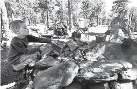  ?? Jeremy Papasso, Daily Camera file ?? Davion Nickens, 6, at left, and his brother Wyatt, 4, cook hot dogs on the campfire with their mother Anna, at right, in an area of National Forest near Gordon Gulch near Nederland in 2019.