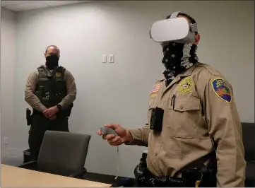  ?? PHOTOS BY ALAN DEP — MARIN INDEPENDEN­T JOURNAL ?? Deputy Braeden Ross watches Deputy Brandon Brame try a set of the sheriff department’s new virtual reality goggles at headquarte­rs in San Rafael on Thursday. The devices are being used to train deputies on de-escalation techniques and responding to mental health emergencie­s.