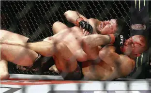  ?? Mike Stobe/AFP ?? Georges St-Pierre (embaixo) estrangula o inglês Michael Bisping para levar o cinturão dos médios do UFC, no Madison Square Garden, em Nova York (EUA)