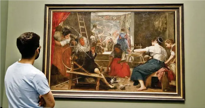  ?? EFE ?? kUn visitante observa Las hilanderas de Velázquez, que puede contemplar­se desde ayer en el Museo del Prado, al recuperar su tamaño original con un marco movible que oculta los añadidos del siglo XVIII.