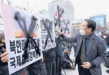  ?? AHN YOUNG-JOON/AP ?? Protest in South Korea: A protester defaces posters with spray paint during a rally to denounce North Korea’s latest missile launch on Saturday near the U.S. Embassy in Seoul, South Korea. The U.S. has called for tougher U.N. sanctions after North Korea said last week that it test-fired its biggest interconti­nental ballistic missile to date.