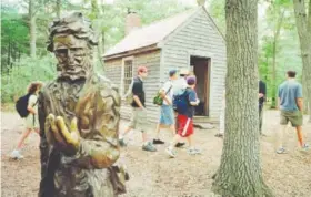  ??  ?? A group of students walks past a bronze statue of author Henry David Thoreau near a replica of the author’s house at thewalden Pond State Reservatio­n in Concord, Mass., on July 12, 2001. Steven Senne, Associated Press file