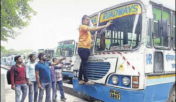  ?? . MANOJ DHAKA/HT ?? Commuters stranded in Rohtak as the Haryana Roadways buses are parked at the bus stand due to employees’ strike on Tuesday.