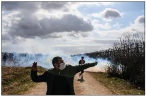  ?? (AP/Emrah Gurel) ?? Migrants inside Turkey clash with Greek riot police Saturday as they try to pull down a fence to break through the border into Greece near the village of Kastanies. At least two migrants were injured as Greek forces responded with volleys of tear gas while groups of mostly young men, some shouting “Allah is great” and others shouting “open the border,” worked to tear down the fence.