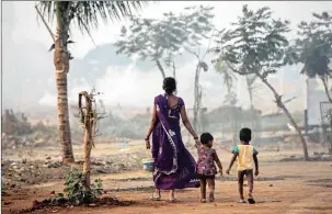  ?? PICTURE: EPA ?? HARD CHOICE: A woman carries a bucket as she and her children prepare to relieve themselves in the open on the outskirts of Mumbai, India. The UN wants to provide water and sanitation for all by 2030.