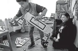  ?? ?? Zaylyn Alvarado, 7, left, prepares to put out a racing track, while his mother Dominique, right, watches at their home on Monday in Milwaukee. Zaylyn has been experienci­ng anxiety episode due to a situation at home.