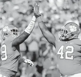  ?? STREETER LECKA/GETTY IMAGES ?? Clemson’s James Edwards, left, and Christian Wilkins celebrate after a defensive stop against Louisville on Saturday.