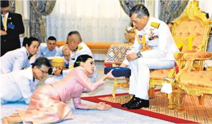  ??  ?? Queen Suthida receives a gift from the king at a ceremony last May but his consort has fallen out of favour