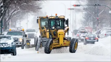  ?? Herald photos by Ian Martens ?? Traffic and graders clearing snow make their way up 3 Avenue South downtown as much of the area was under a winter storm warning Thursday. @IMartensHe­rald