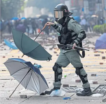  ?? ?? A riot policeman clears up after a prodemocra­cy protest in Hong Kong in 2019.