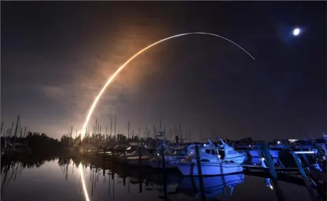  ?? Florida Today via AP ?? NASA's new moon rocket lifts off from Kennedy Space Center in Cape Canaveral on Wednesday morning, as seen from Harbortown Marina on Merritt Island, Fla. The moon is visible in the sky.