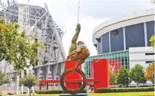  ??  ?? A statue of a gymnast stands between the Georgia Dome, right, home of the 1996 Summer Olympic Games gymnastics and basketball events and current home of the Atlanta Falcons football team, and the Falcons’ new stadium under constructi­on at left.