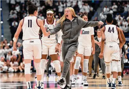  ?? Jessica Hill/Associated Press ?? UConn’s Paige Bueckers, center, reacts after UConn’s Lou Lopez-Senechal, left, hit a 3-pointer at the end of the first quarter against South Carolina, Sunday, in Hartford.