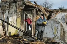  ?? ANDRIY ANDRIYENKO/AP ?? A woman recovers food items outside her home Thursday after it was destroyed by a Russian drone attack in Zaporizhzh­ia, a city in southeaste­rn Ukraine.