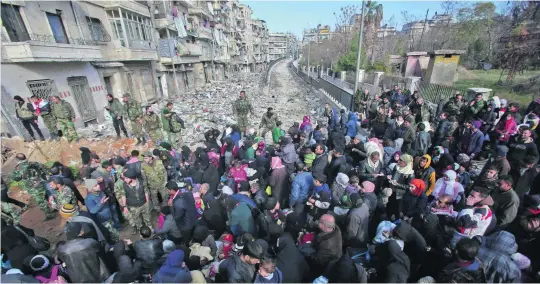  ?? Youssef Karwashan / AFP ?? Residents hoping to flee the violence in the Maysaloun neighbourh­ood of northern Aleppo gather at a checkpoint manned by pro-government forces.