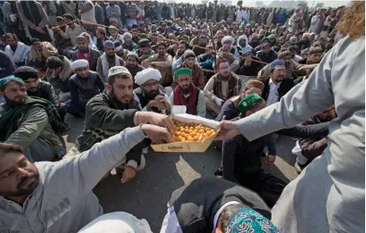  ?? AP ?? An activist distribute­s sweets to fellow protesters following resignatio­n of law minister Zahid Hamid in Islamabad on Monday. —