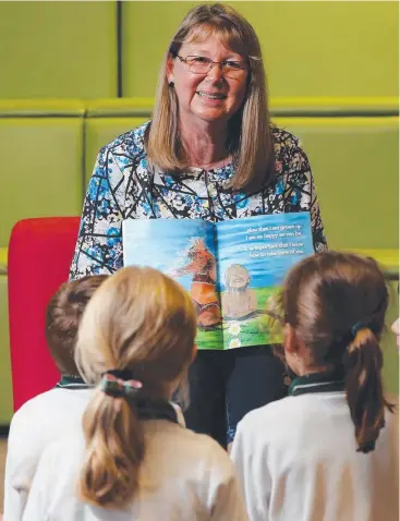  ?? Picture: STEWART McLEAN ?? VITAL: Book author Patricia Barden reads to children at Whitfield State School.