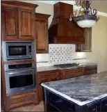  ??  ?? The open kitchen blends stained-wood and painted cabinetry with granite, travertine and stainless steel.