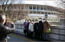  ?? AP-Jae C. Hong ?? Tourists wear masks as they pose for photos at the New National Stadium, a venue for the opening and closing ceremonies at the 2020 Olympics in Tokyo, on Sunday.