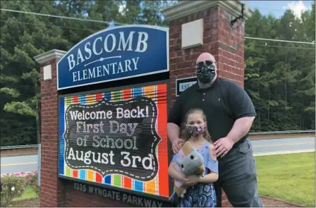  ?? THE ASSOCIATED PRESS ?? John Barrett and his daughter Autumn pose for photos outside Bascomb Elementary School in Woodstock, Ga., July 23. Barrett says he will educate his daughter virtually and keep her out of in-person classes in Cherokee County schools, even though he’s worried she will fall behind on her special education plans, because of concerns about COVID-19’s spread. Cherokee County, near Atlanta, is one of many districts nationwide that gave parents a choice between in-person and all-online classes this fall.