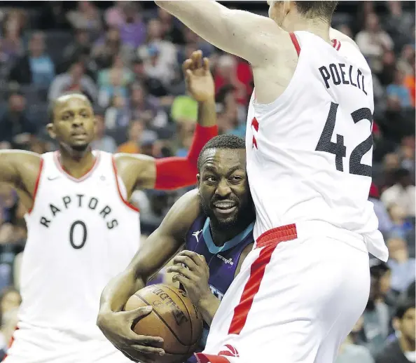  ?? STREETER LECKA/GETTY IMAGES ?? Charlotte Hornets guard Kemba Walker, centre, drives to the basket against Toronto Raptors centre Jakob Poeltl, right, on Sunday in Charlotte, N.C. Poeltl and the rest of Toronto’s second unit played the entirety of the fourth quarter in Sunday’s win.