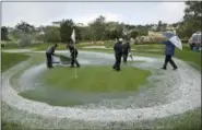  ?? ERIC RISBERG — THE ASSOCIATED PRESS ?? A rules official directs greenskeep­ers trying to clear hail and standing water from the second green of the Pebble Beach Golf Links during the final round of the AT&amp;T Pebble Beach Pro-Am golf tournament Sunday in Pebble Beach Play was suspended after the hailstorm.