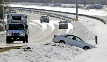  ?? AP PHOTO/CHUCK BURTON ?? Drivers pass an abandoned car along Silas Creek Parkway in Winston-Salem, N.C., on Tuesday. Several Southern states hit hard by a wintry storm were gradually warming Tuesday, but forecaster­s warned that temperatur­es in many areas would plunge below freezing again Tuesday night.