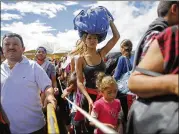  ?? ARIANA CUBILLOS / ASSOCIATED PRESS 2016 ?? A woman carries a bundle on her head last summer as she waits in line to cross the border from San Antonio, Venezuela, into Colombia over the Simon Bolivar Internatio­nal Bridge.