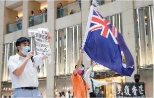  ?? (Tyrone Siu/Reuters) ?? A PRO-DEMOCRACY demonstrat­or waves the British colonial Hong Kong flag yesterday as another one holds a sign during a protest against new national security legislatio­n in Hong Kong.