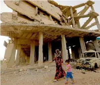  ?? AFP ?? A Syrian woman walks past destroyed buildings in Kobane. The city was heavily damaged in battles against Daesh militants. —