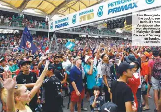  ?? – REUTERSPIX ?? Fans throng into the track to see Redbull’s Max Verstappen who won the Formula 1 Malaysian Grand Prix race at Sepang on Sunday.