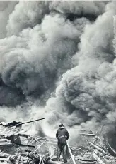  ?? ?? Alex’s iconic image of a firefighte­r tackling the Timex factory blaze in 1966 and, above, a lady in the Ward Road Library reading room in 1960.