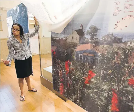  ?? — CP FILES ?? Tracey McCallum displays a mural depicting the former Africville, a black community in north Halifax that was razed almost 50 years ago, in the rebuilt Seaview African United Baptist Church.