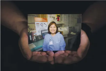  ?? DAI SUGANO — STAFF PHOTOGRAPH­ER ?? A photograph of Celia Marcos, a Filipino American nurse vho died from COVID-19 in April, is held by her 25-year-old son, John Paul Marcos, in Daly City. “I try not to think about her death too much. It’s more just — hov she liued, and vho she vas,” John Paul said.