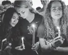  ?? USA TODAY NETWORK ?? Sidney Ho, from left, Jordan Strauss and Kendall Edgren attend a vigil Thursday in Parkland, Fla.