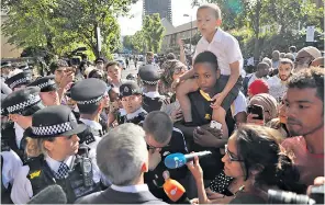  ??  ?? Members of the public, top, grieve for victims of the fire. Above, Sadiq Khan, the mayor, is harangued by seven-year-old Kai Ramos