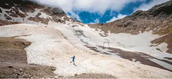  ?? MICHAEL PROBST/AP ?? A youth takes a jog across remnants of a recently melted glacier June 25 on Zugspitze mountain near Garmisch-Partenkirc­hen, Germany.