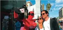  ??  ?? Superhero impersonat­or and actor Dan Inigo, left, uses a tourist's smartphone to take a selfie on Hollywood Boulevard in Los Angeles.