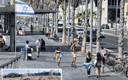  ?? PHOTO: REUTERS ?? Life goes on? People walk in a street, after Iran launched missiles and drones towards Israel, in Tel Aviv, yesterday. Left: The remains of a rocket booster engine lie near Arad, Israel, yesterday.