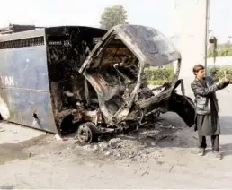  ?? Reuters ?? A passerby takes a selfie in front of a police prison van destroyed during clashes.