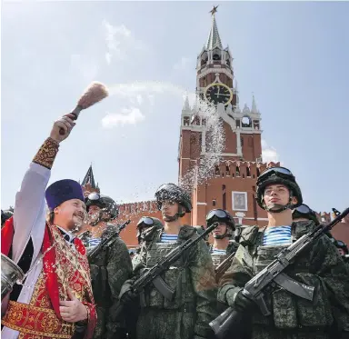  ?? ALEXANDER ZEMLIANICH­ENKO / THE ASSOCIATED PRESS ?? A Russian Orthodox priest blesses paratroope­rs earlier this month in Moscow’s Red Square.