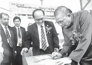  ??  ?? SIMBOLIK: Fadillah menandatan­gani dokumen sebagai simbolik perasmian Kejohanan Taekwondo ITF Sekolah-Sekolah Sarawak dan Jemputan Kebangsaan 2017 di Kuching semalam sambil disaksikan Master Johnny (tengah) serta tetamu jemputan lain.