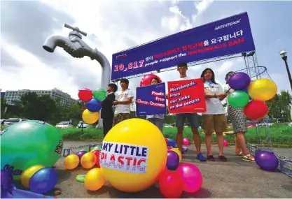  ??  ?? SEOUL: Members of the environmen­tal group Greenpeace hold placards and balls symbolizin­g microplast­ics from cosmetic products during a campaign to support a microbeads ban, at the Han river on August 9, 2016. —AFP