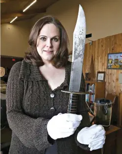  ?? Rod Aydelotte/Waco Tribune-Herald via AP ?? Shelly Crittendon, artifacts and exhibits manager, holds up a 17-inch Bowie knife recently donated to the Texas Ranger Hall of Fame Museum, on Jan. 9 in Waco, Texas. The knife’s scabbard gives a tantalizin­g sign of its true significan­ce. Engraved in a...