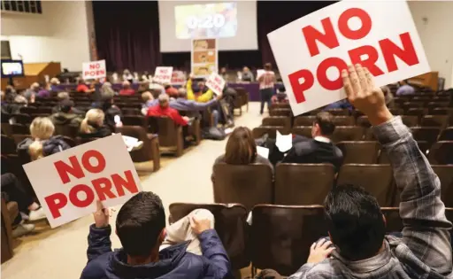  ?? ANTHONY VAZQUEZ/SUN-TIMES ?? Protesters hold up signs Monday night at the Downers Grove North High School Board meeting.