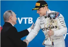  ?? FOTO: DPA ?? Ein Pokal, kein Lewis Hamilton mit auf dem Podium – dafür gratuliert­e Präsident Putin Mercedes-Zweitkraft Valtteri Bottas.